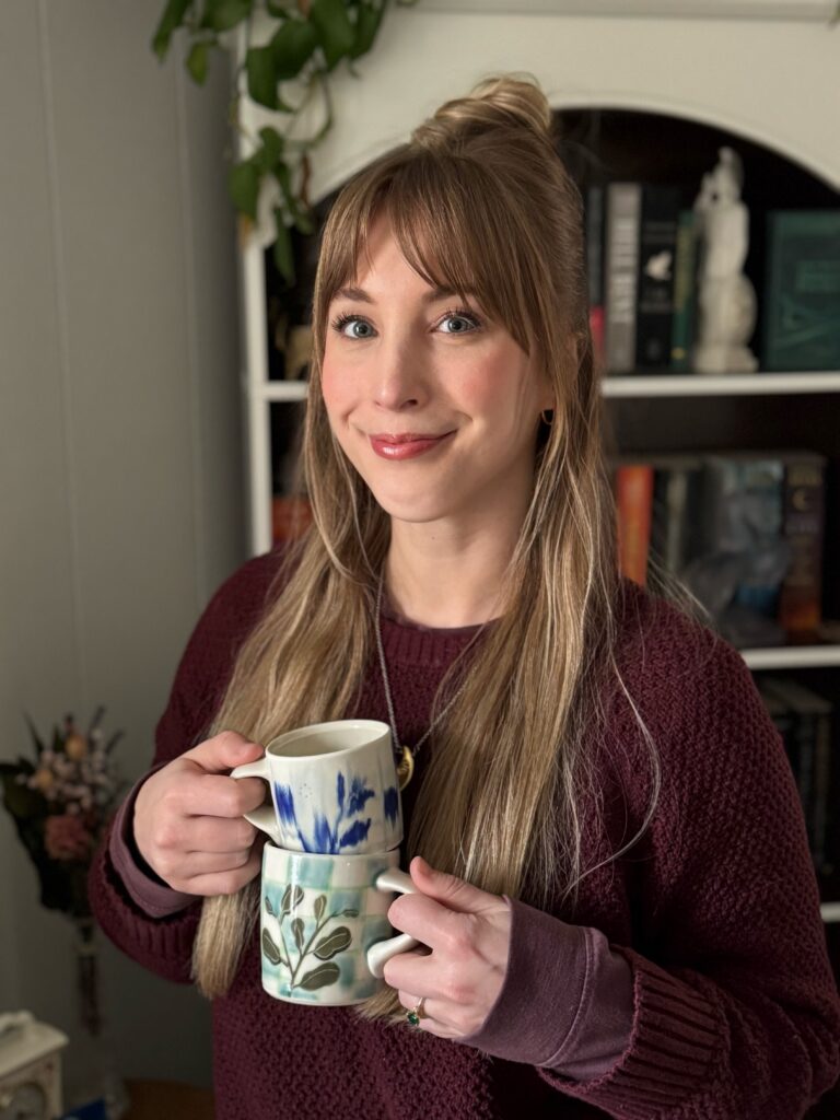 Potter holding two stacked hand-painted mugs