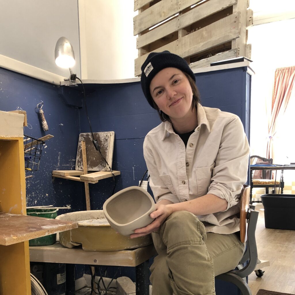 Potter at the wheel holding a freshly thrown bowl